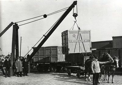 163218 Afbeelding van het overladen van een laadkist van Van Gend & Loos van spoor naar paard en wagen (of andersom) ...
